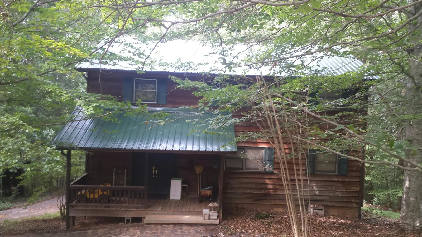 Green metal roof and covered porch on a log cabin in Los Molinos