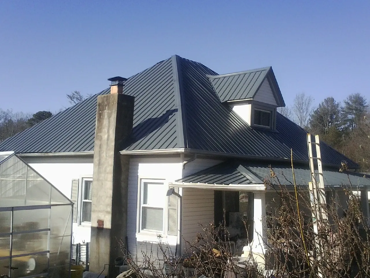 Dark blue standing seam metal roof on a white farmhouse with dormer — Slate & Tile Roof Repair by Roofing Brothers in Los Molinos