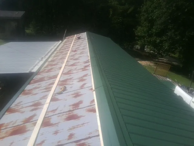 Old rusted panels beside newly installed green metal roofing — Wind Damage Roof Repair by Roofing Brothers in Los Molinos