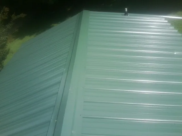 New green metal panels meeting at the ridge of a roof — Flat Roof Repair work by our crew in Los Molinos