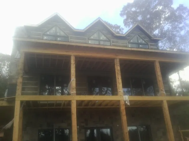 Dormers and porch framing on a large log home under construction — Roof Coating work by our crew in Los Molinos
