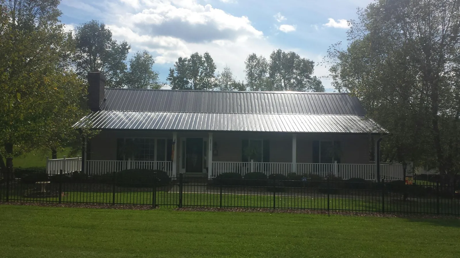 Gray metal roof on a brick ranch with a full width front porch — Gutter Guard Installation work by our crew in Los Molinos