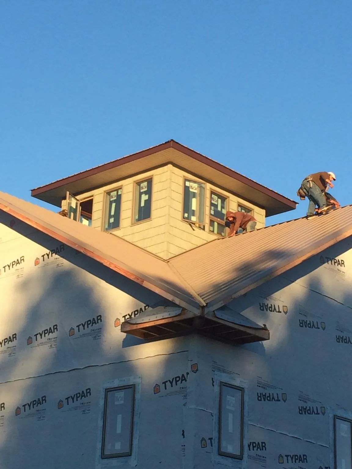 Roofers working around a rooftop cupola on a new metal roof at sunset — Roof Waterproofing in Los Molinos by Roofing Brothers